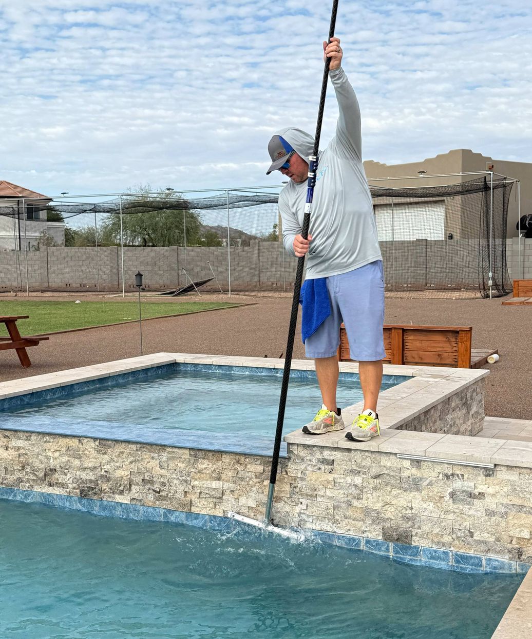 professional pool technician brushing and skimming pool in Anthem Arizona
