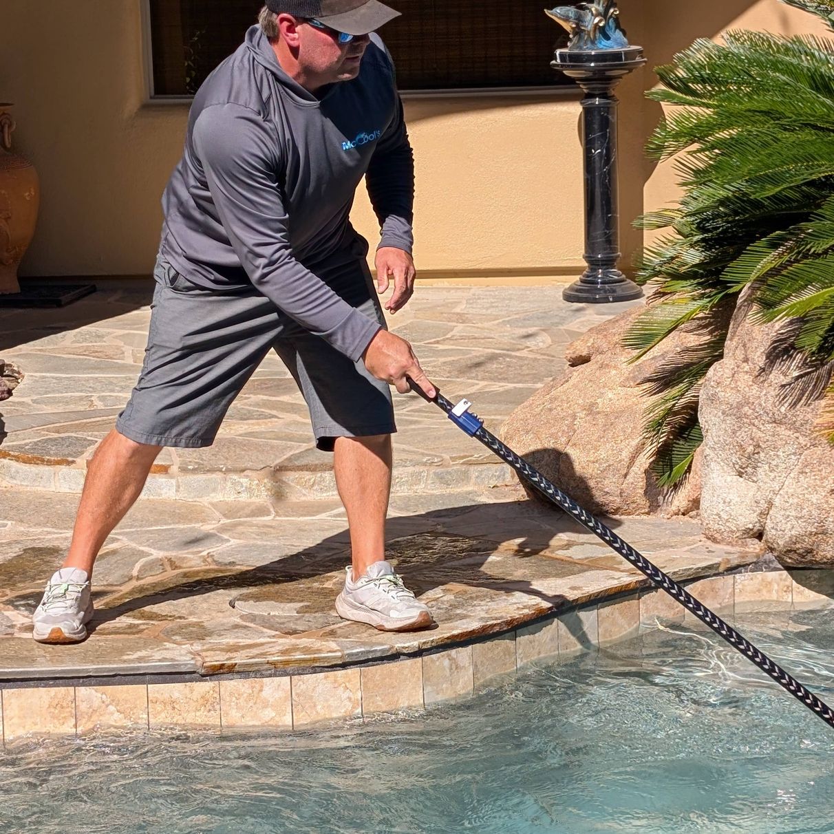 pool technician cleaning pool with brush