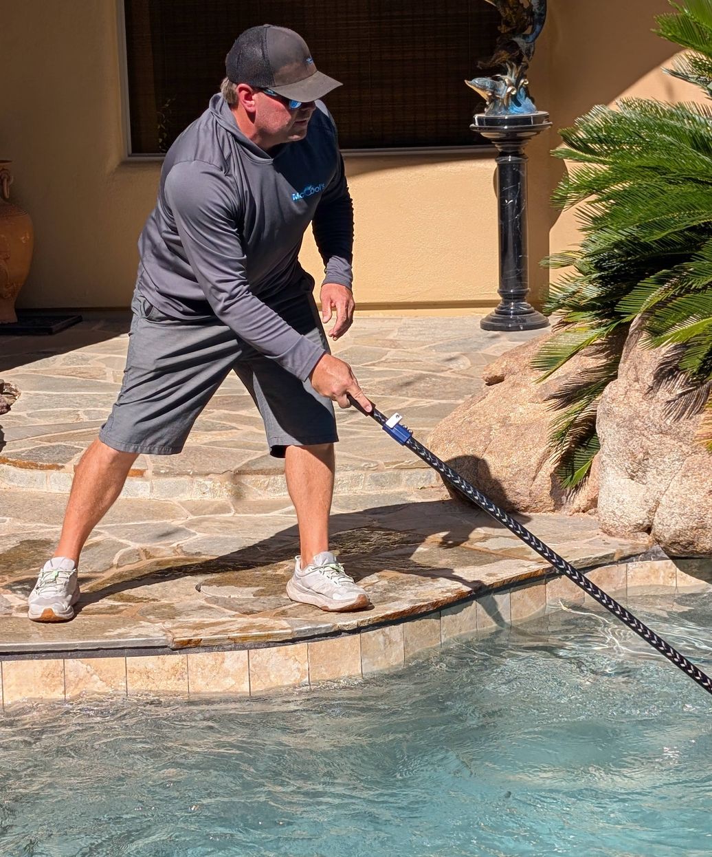 professional pool technician brushing and cleaning pool